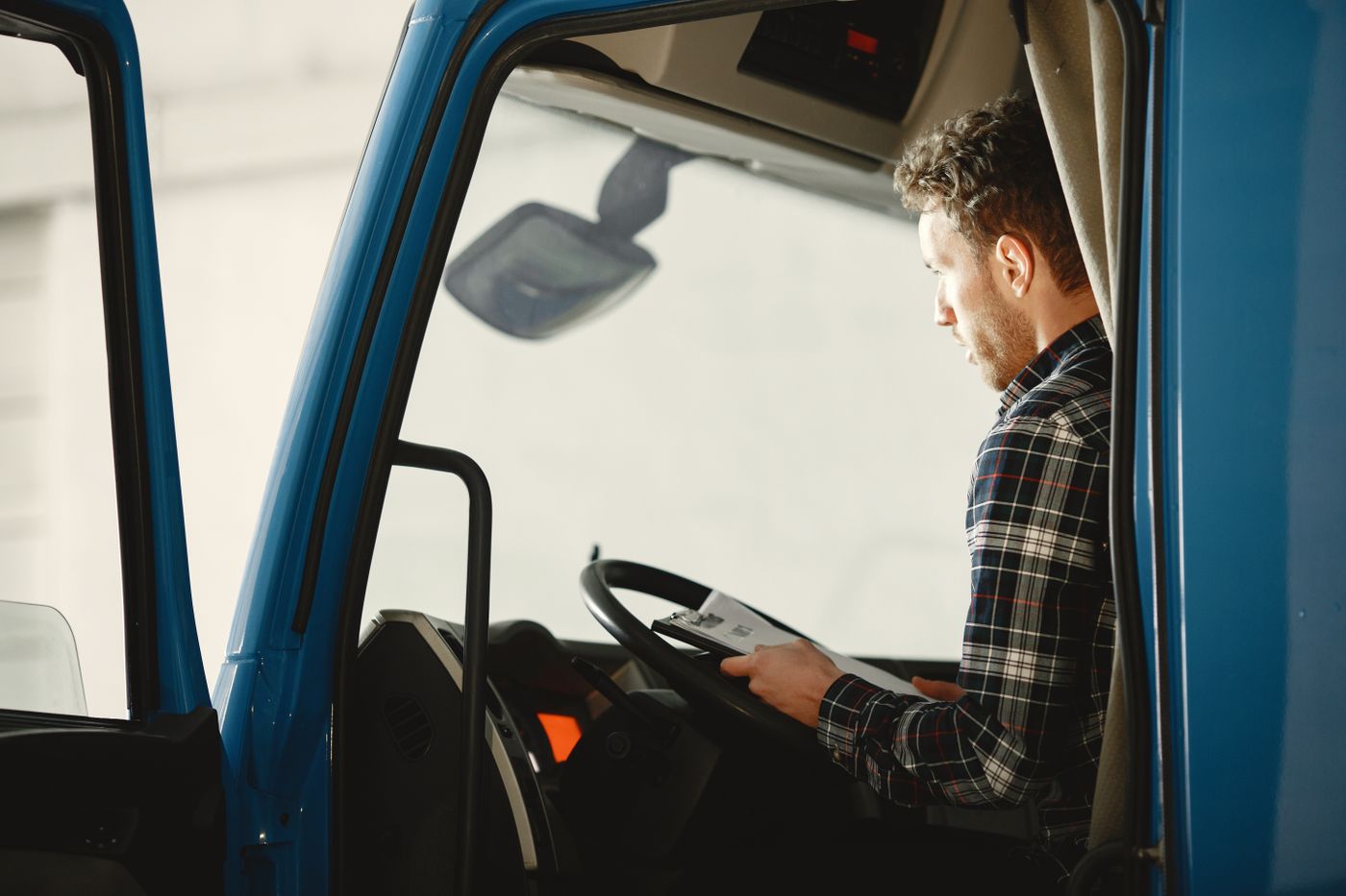 Un camionero en la cabina de su camión revisando la documentación del viaje